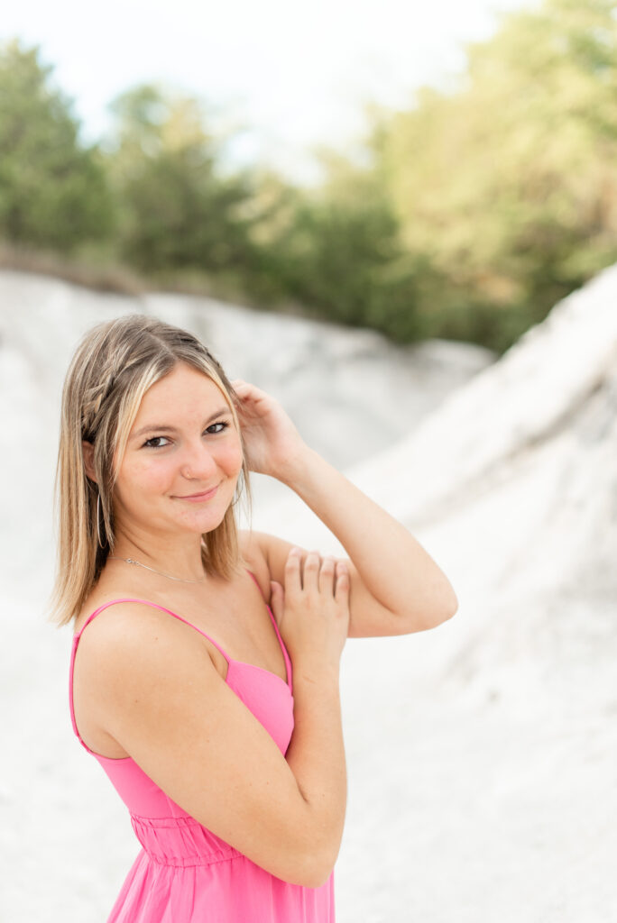 senior girl with right shoulder towards camera and left hand tucking hair behind her ear at white cliffs of conoy