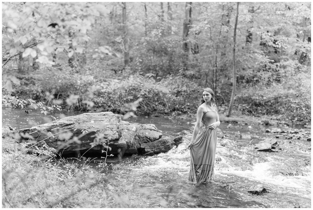 black and white photo of senior girl in long dress standing in shallow water at hibernia park