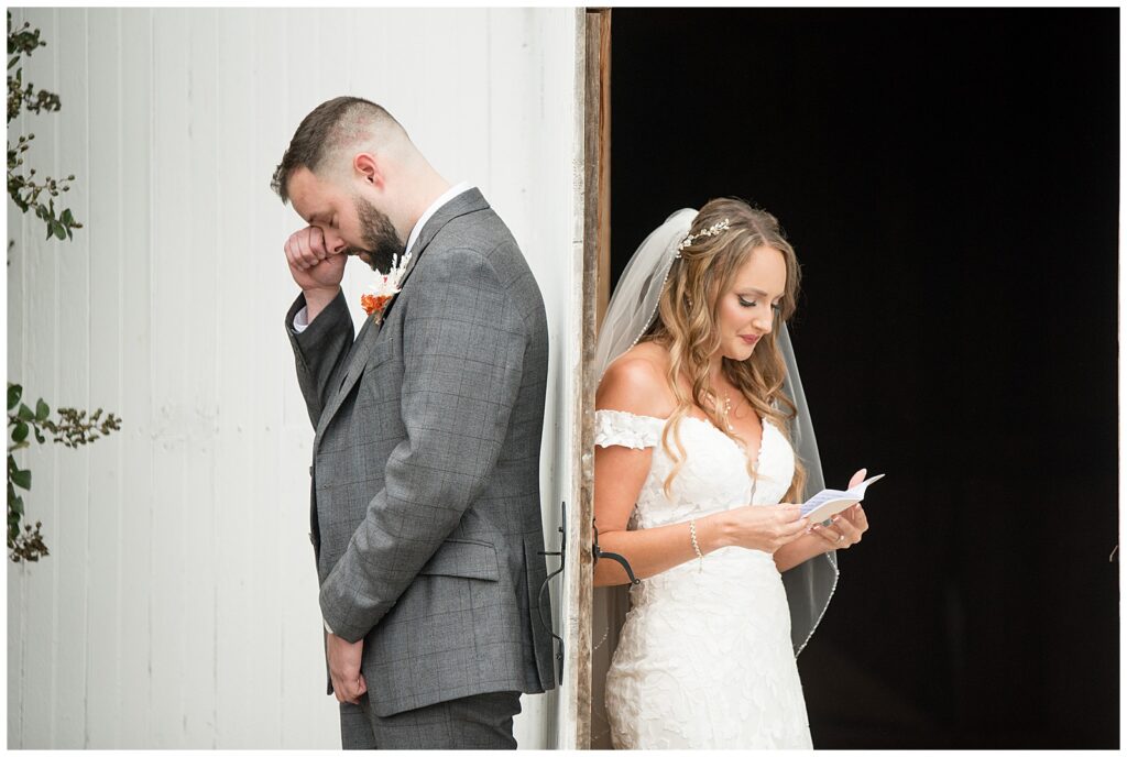 bride and groom stand on their side of white barn door and share their vows before ceremony without seeing each other at lakefield weddings