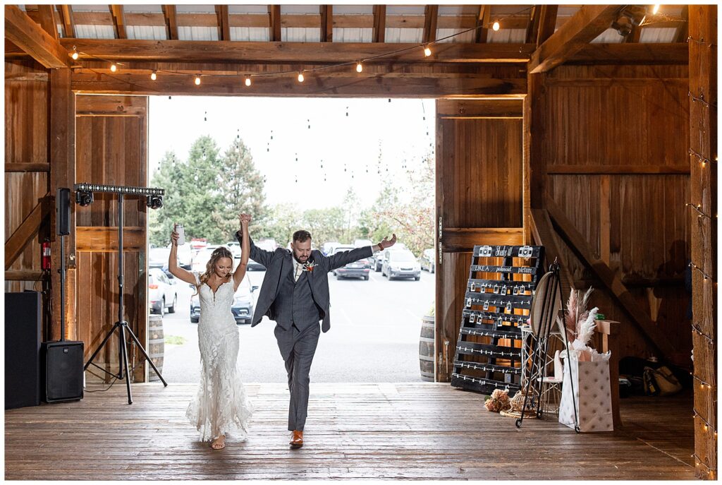 couple entering their barn reception with arms held high as guests cheer at lakefield weddings