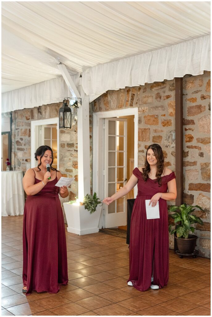 two bridesmaids sharing toast during indoor reception by stone wall at the manor house at prophecy creek