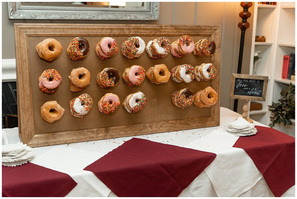fun display of doughnuts on pegboard on white and burgundy table at reception at the manor house at prophecy creek