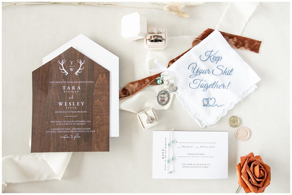 wedding invitation, rings, napkin, and other details on display on white background at lauxmont farms