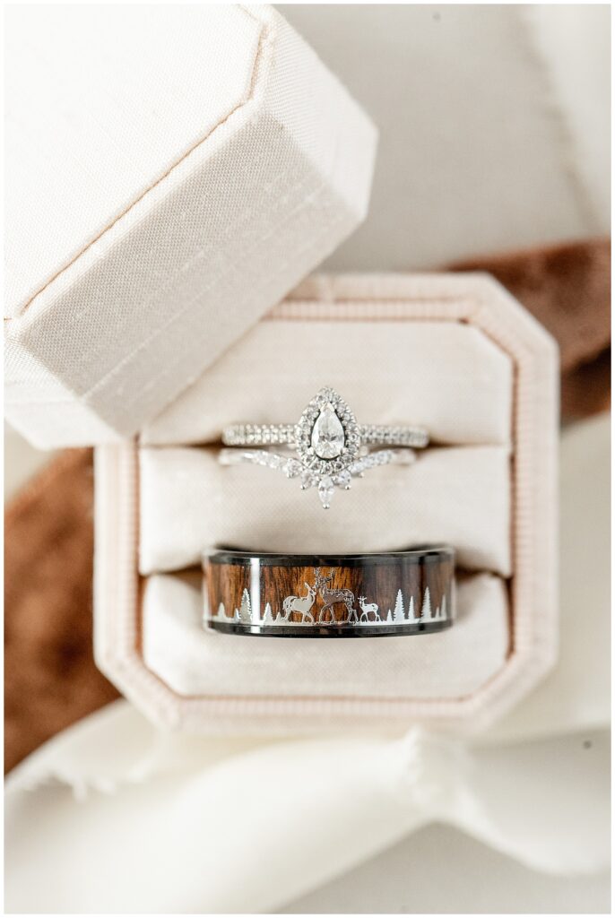 close-up photo of bride's diamond and groom's black, brown, and silver wedding band in velvet box in york county