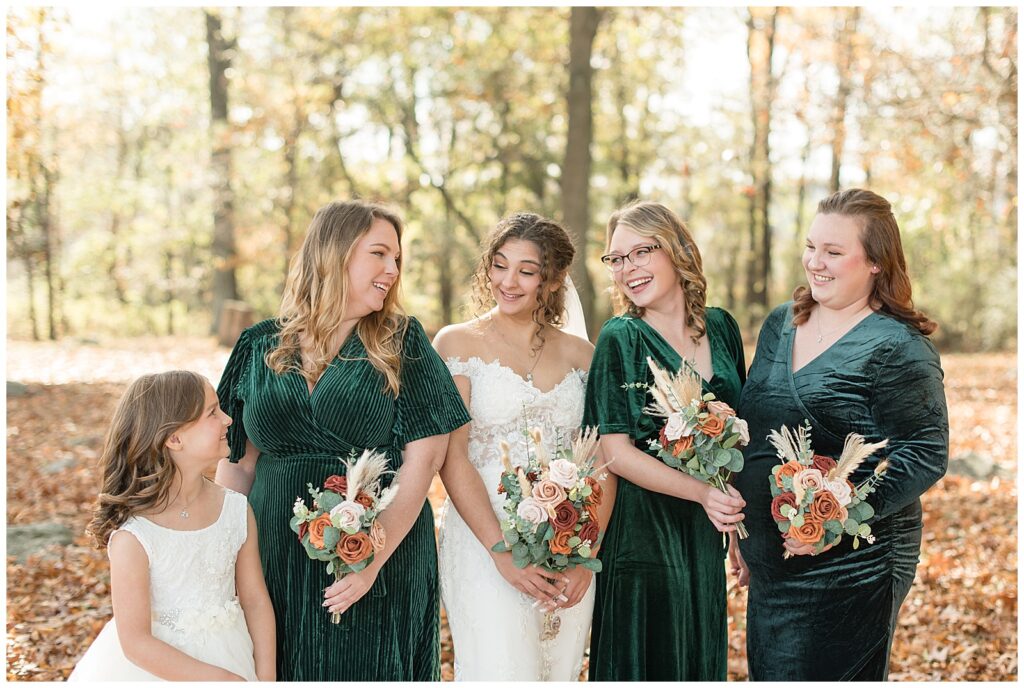 bride surrounded by her three bridesmaids wearing dark green velvet dresses and her flowergirl in white dress at lauxmont farms