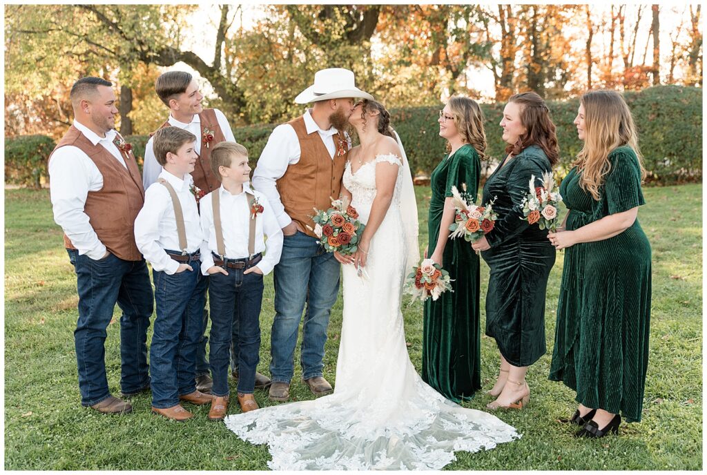 couple surrounded by their bridal party and kissing as they watch on fall day at lauxmont farms in york county