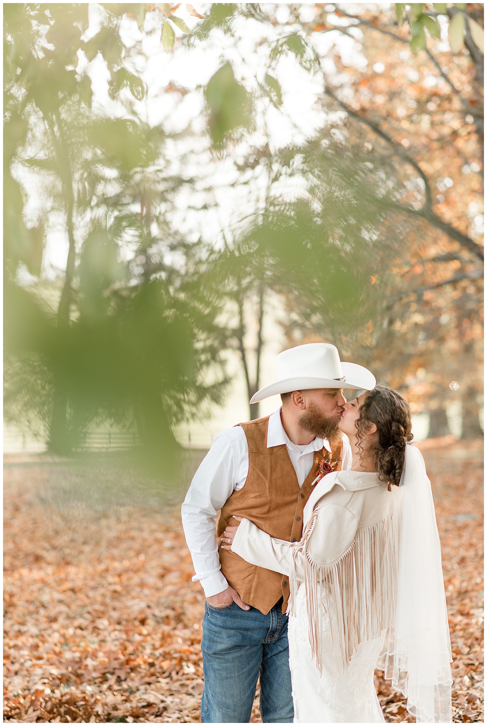 groom kissing his bride as she slightly dips back and his wearing ivory leather fringe cowgirl jacket at lauxmont farms