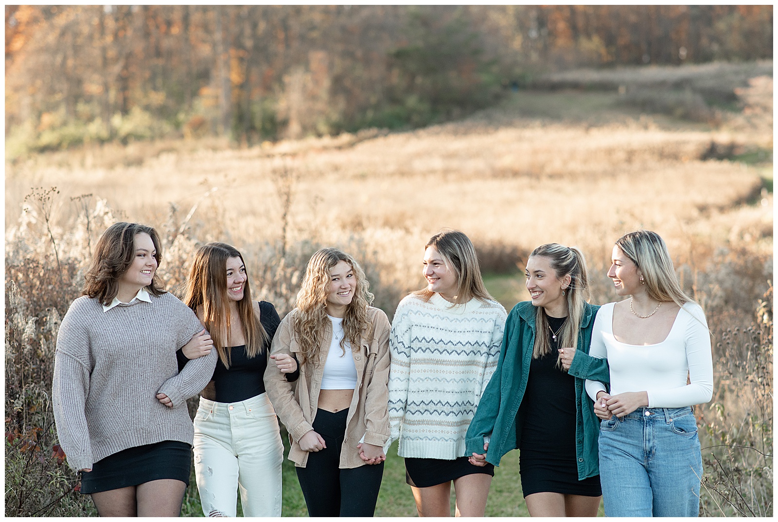 six senior girls hold hands and looking at each other by tall wild grasses at sunset at middle creek in lancaster pennsylvania