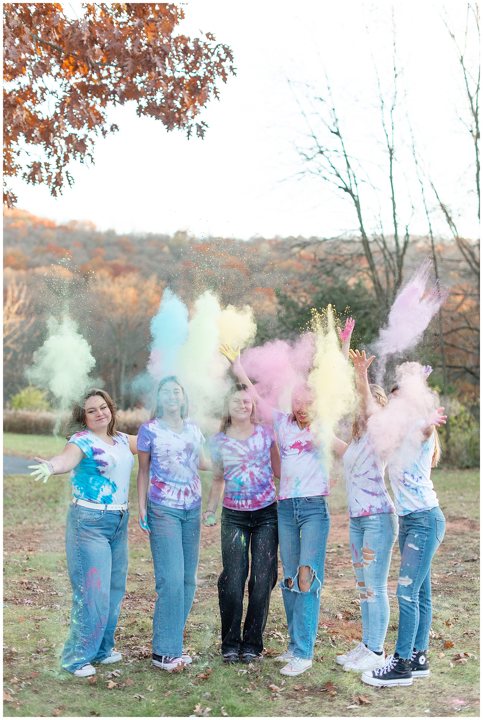 senior girls standing together and throwing colored powder into the air at middle creek wildlife management area
