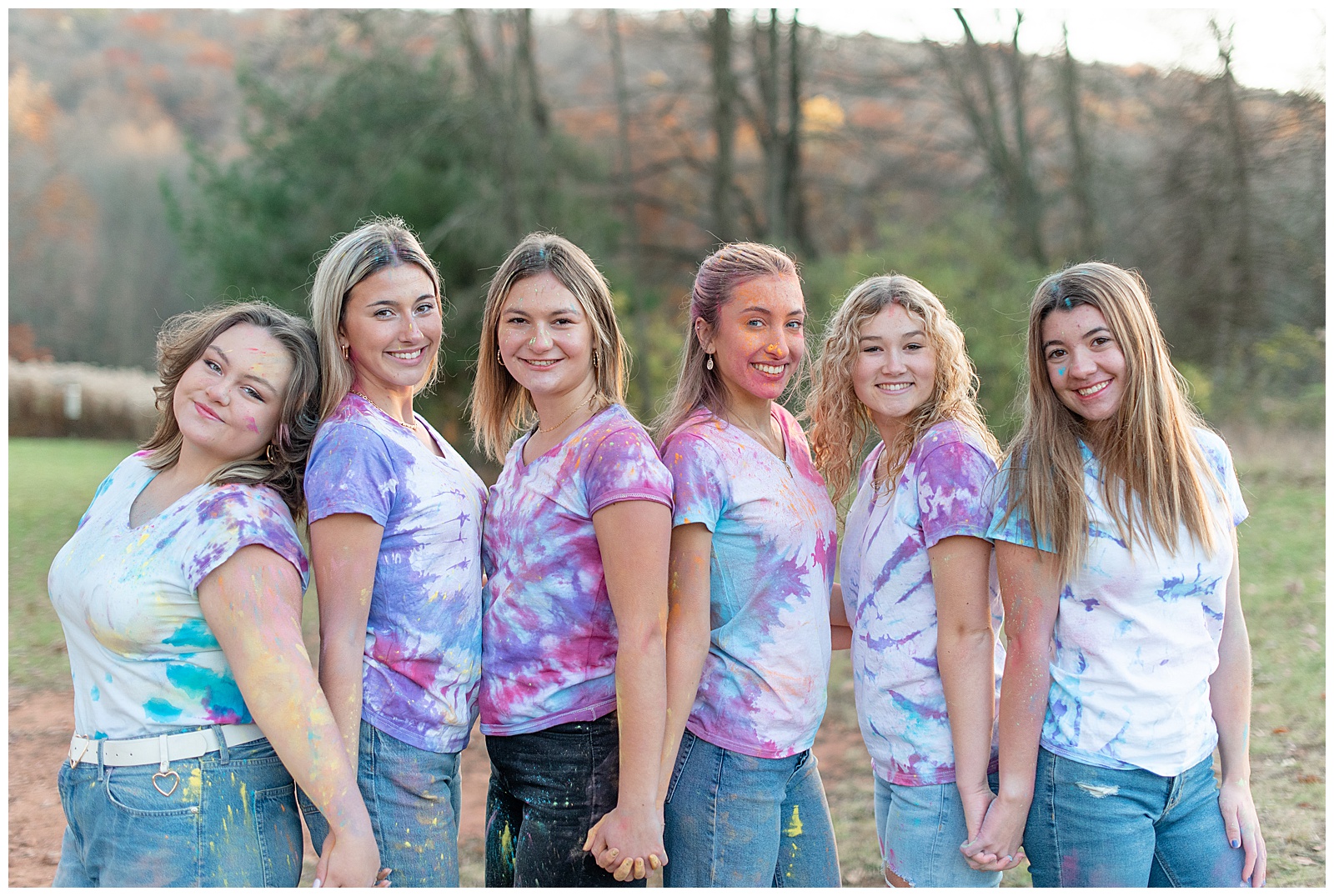 senior girls holding hands and standing close together in different directions smiling at camera at middle creek 