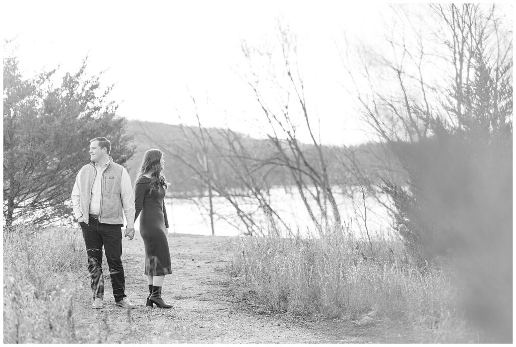 black and white photo of couple holding hands and looking in opposite directions by river in lancaster pennsylvania