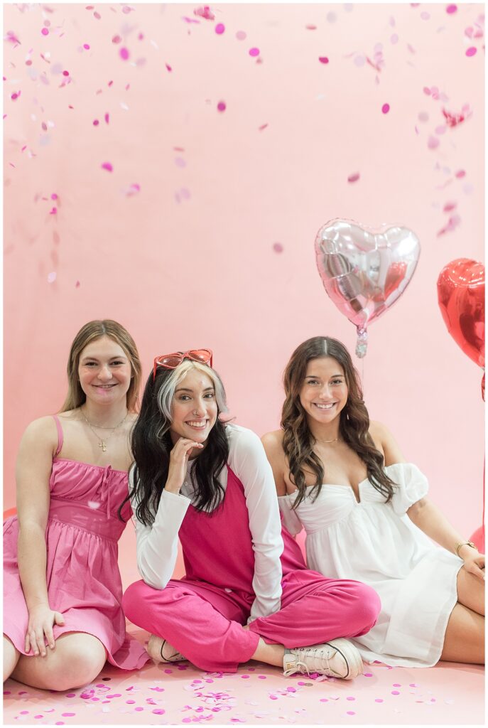 three senior girls sitting on the floor by light pink wall and heart-shaped balloons at haven studios in lancaster pennsylvania