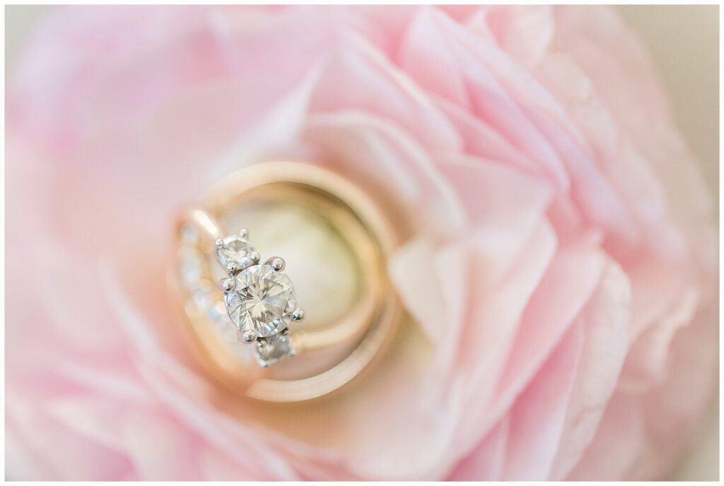bride's gold diamond ring resting on groom's ring on top of pink rose in leola pa