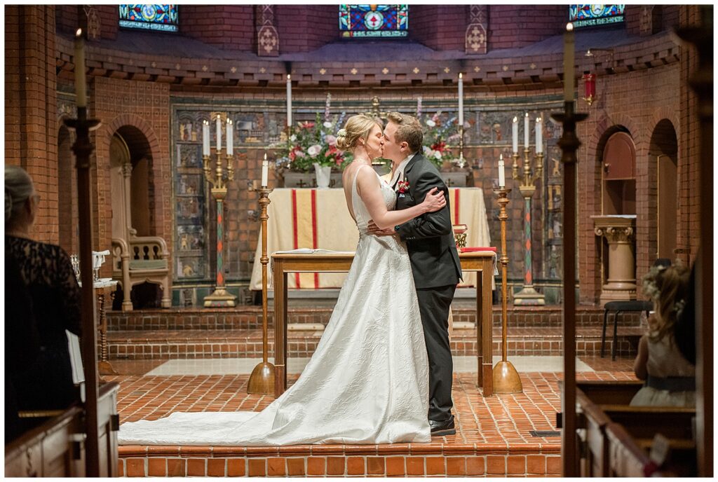 bride and groom sharing their first kiss during wedding ceremony inside church in lancaster city