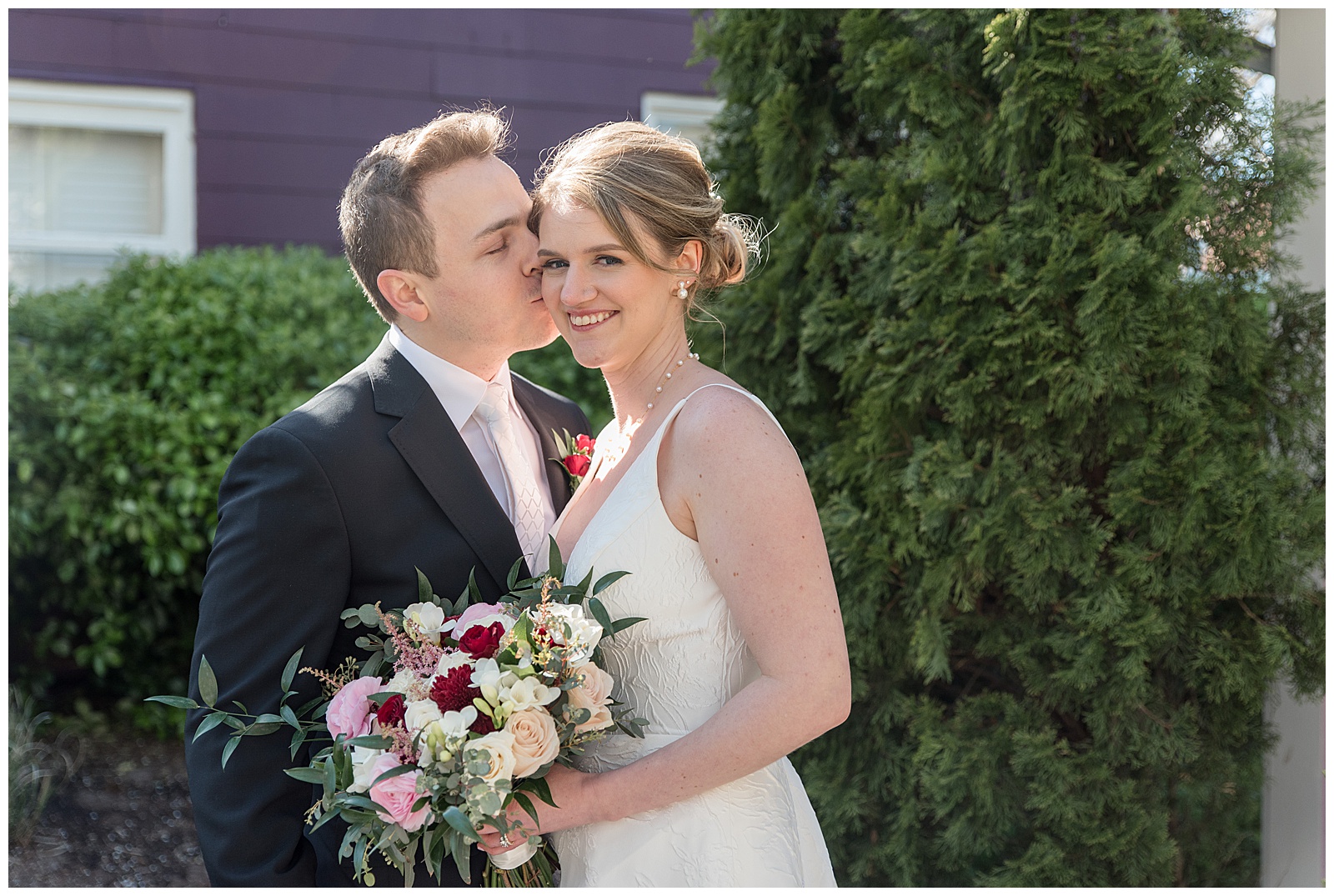 groom kissing his bride's right cheek as she smiles at the inn at leola village in lancaster pa