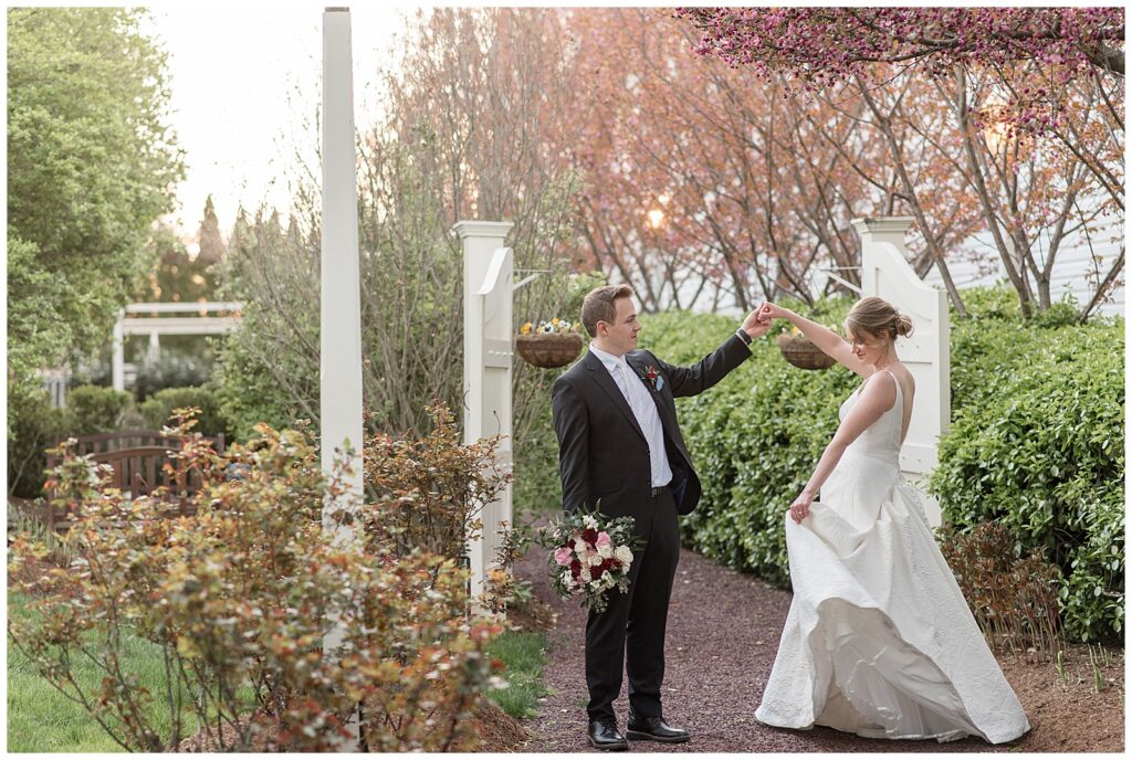 groom twirling his bride by cherry blossom outside the inn at leola village on spring day