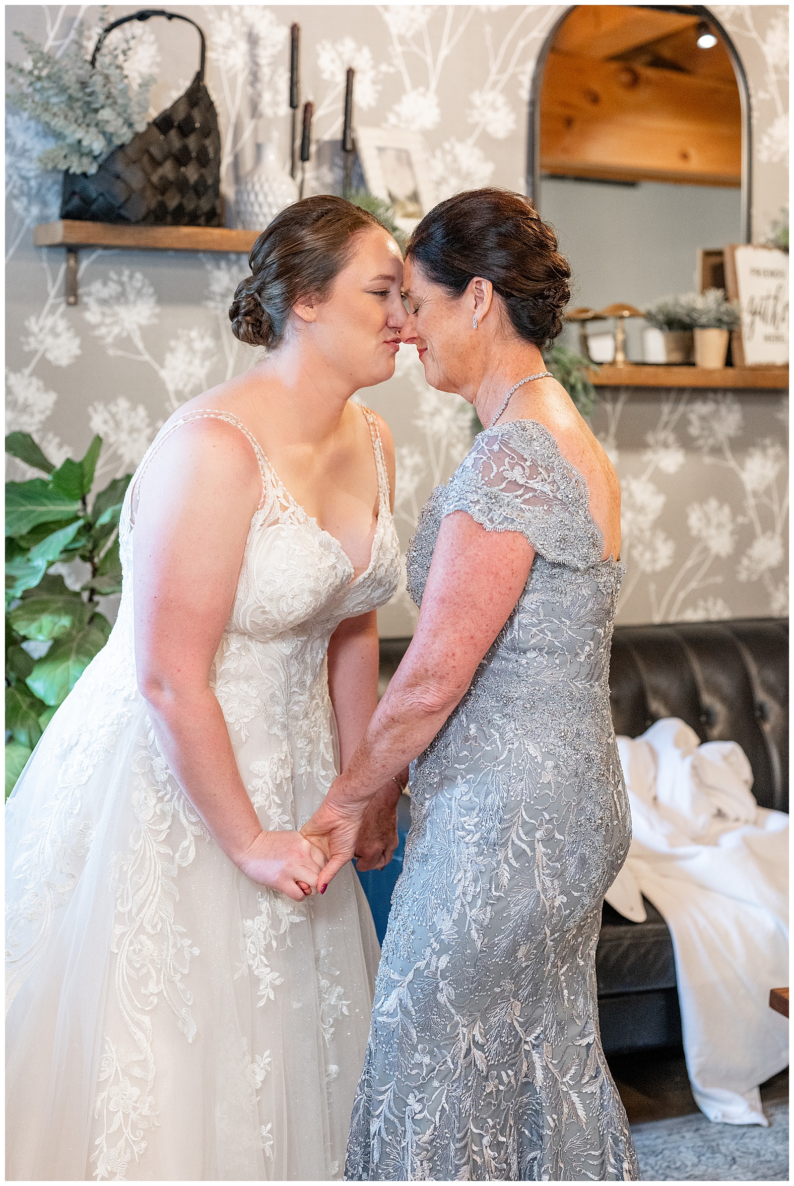 bride and her mom holding hands and touching foreheads together in bridal suite at brick gables