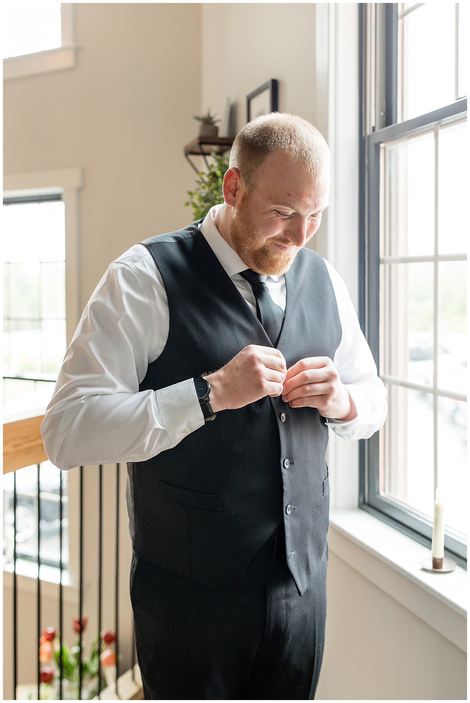 groom looking down and buttoning his black vest before wedding at brick gables in lancaster county