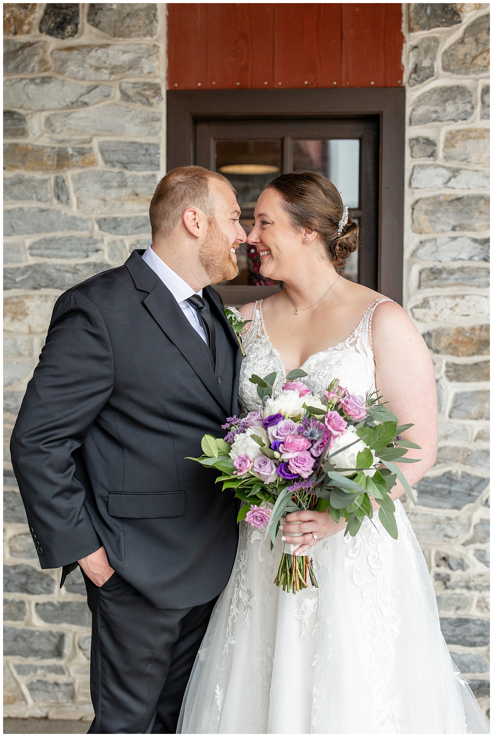 bride and groom touching noses by stone wall at brick gables in lititz pennsylvania