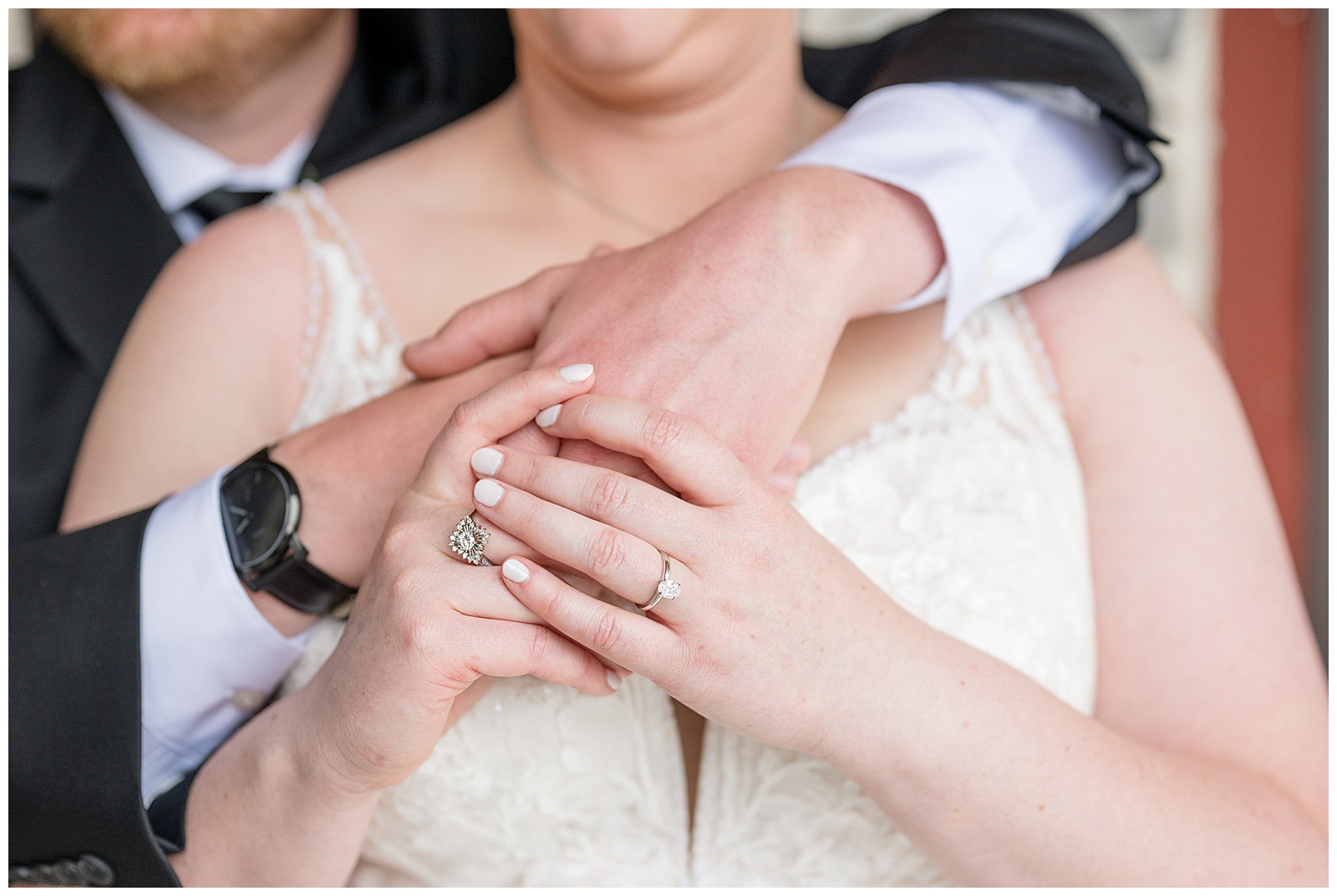 closeup photo of groom wrapping his arms around bride and her holding his hands at brick gables