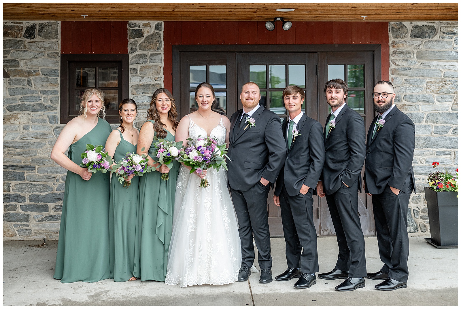 couples standing with their three bridesmaids and three groomsmen by stone wall of barn at brick gables