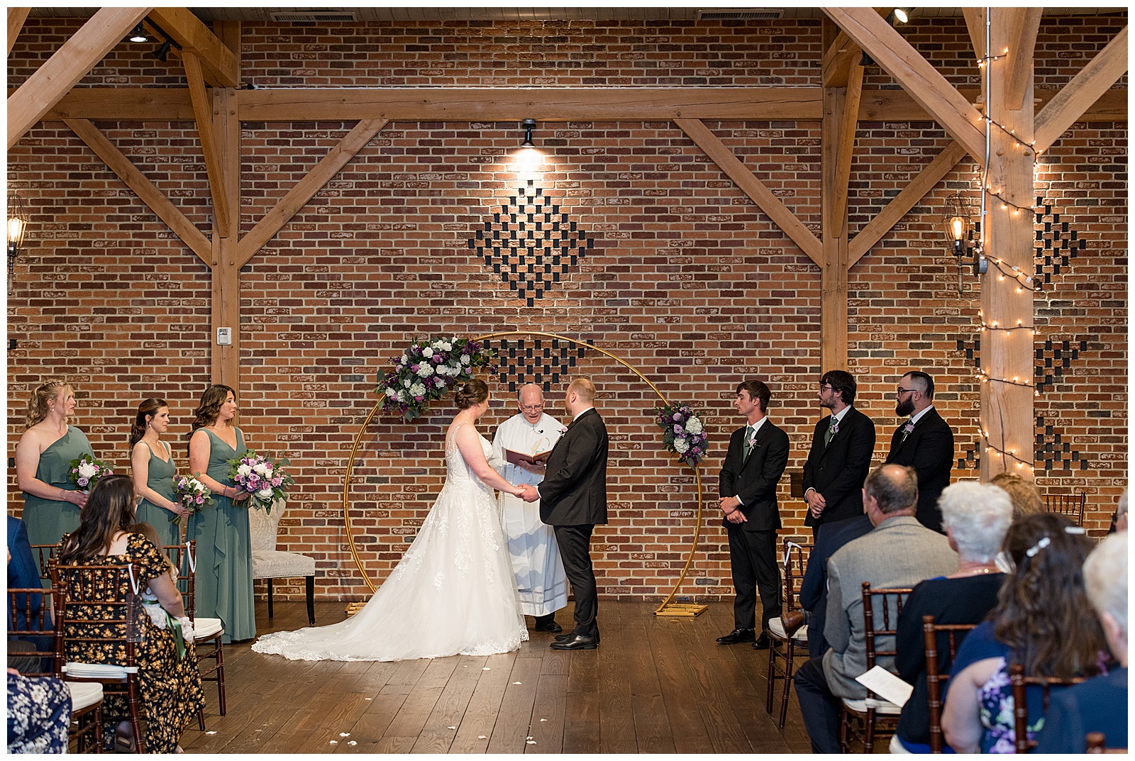 couple holding hands during barn wedding ceremony by beautiful brick wall at brick gables
