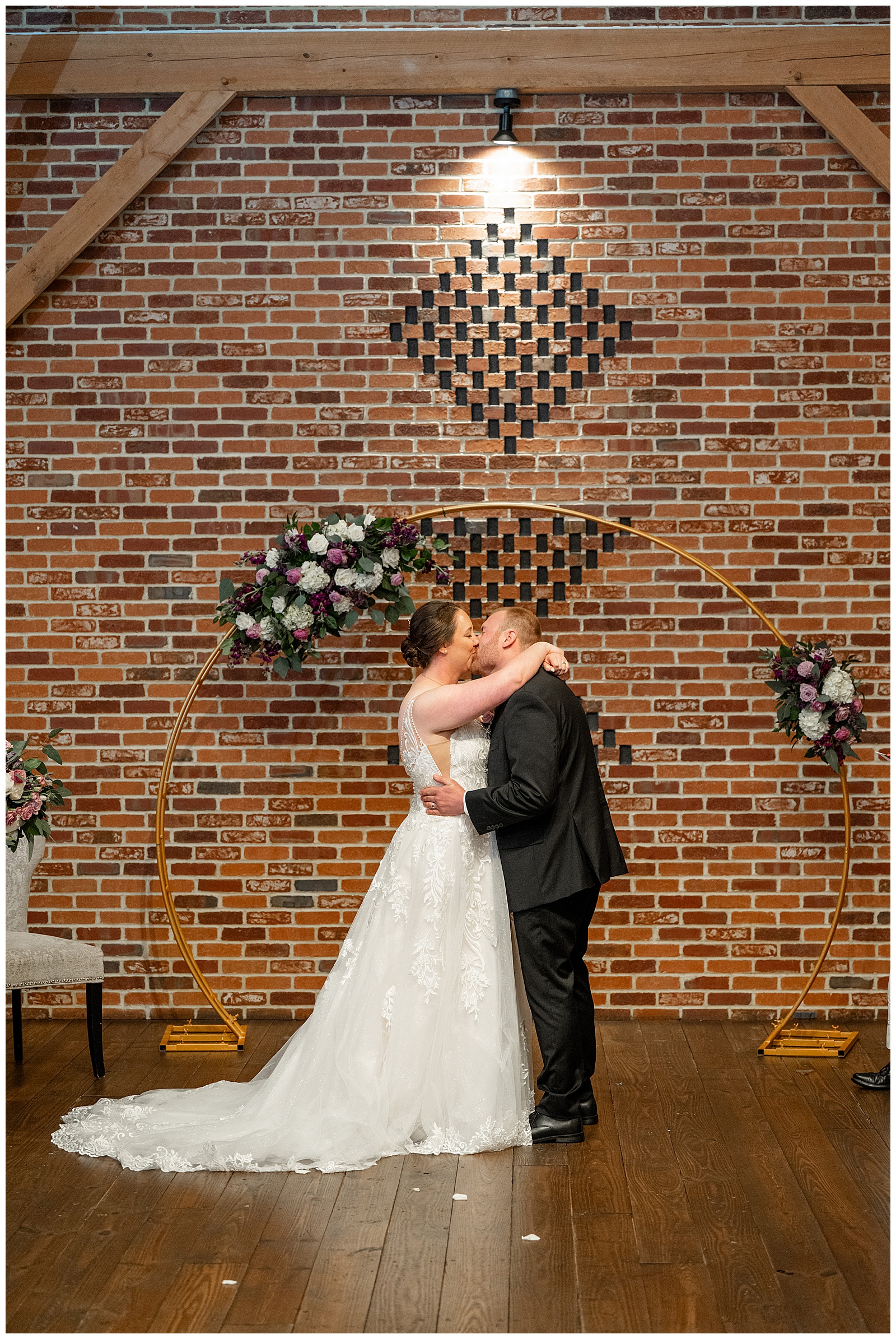 couple sharing their first kiss during barn wedding ceremony at brick gables