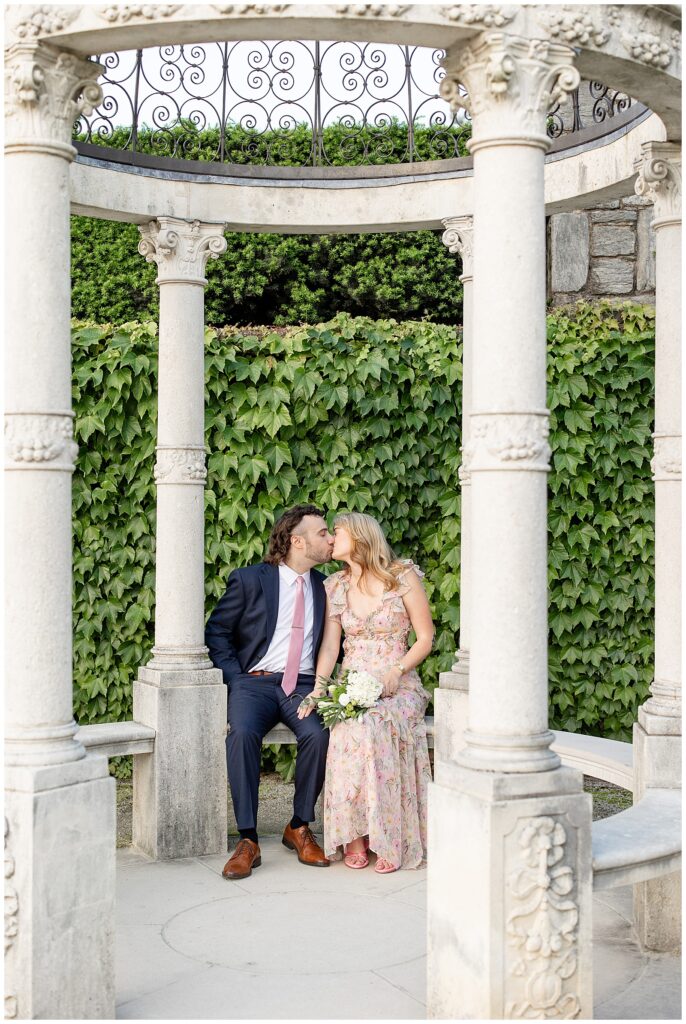 couple sitting in concrete structure by ivy wall kissing at longwood gardens in pennsylvania