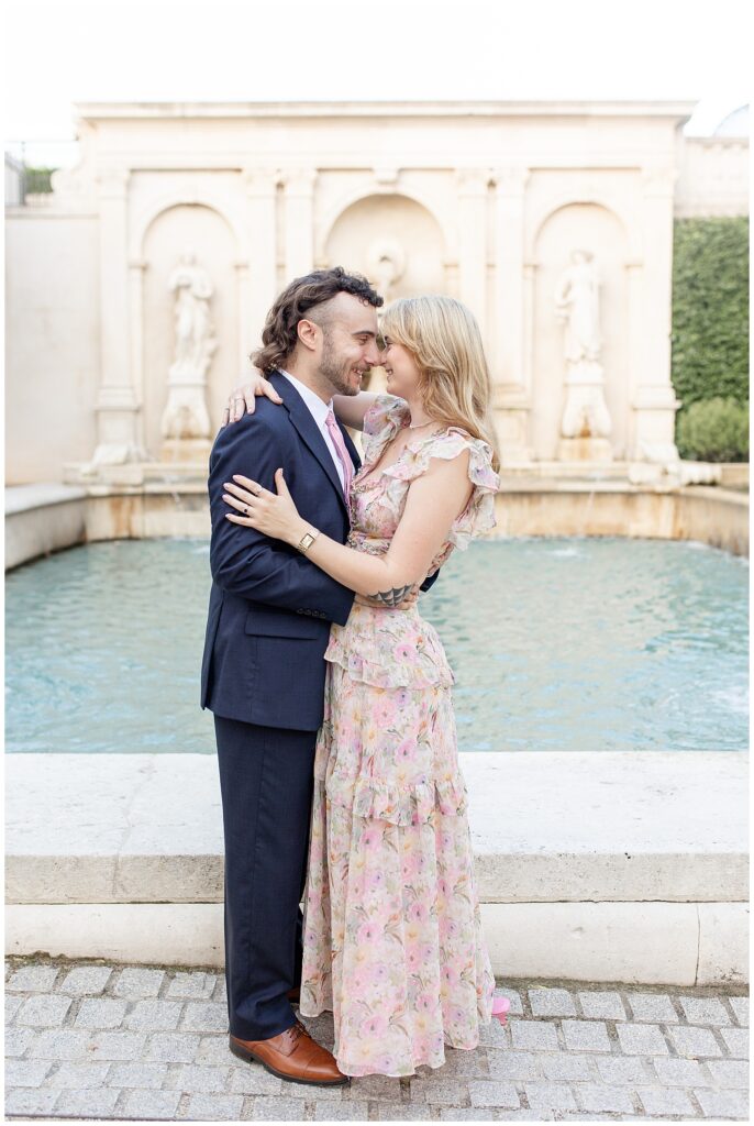 engaged couple hugging with noses touching by fountain at longwood gardens in kennett square