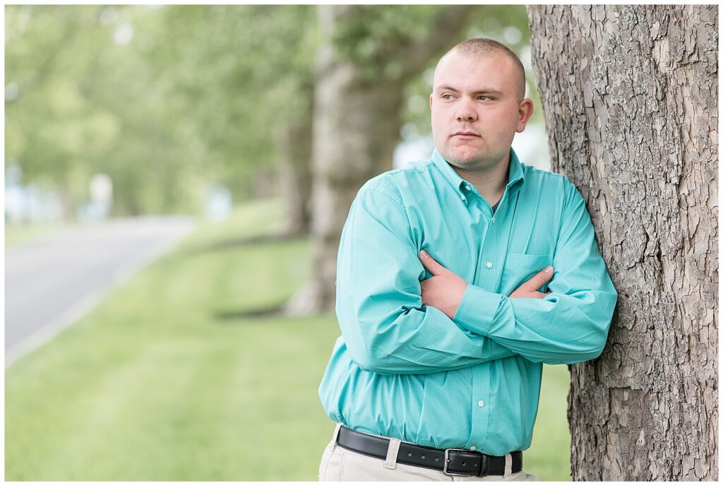 senior guy leaning against tree with arms crossed and looking right at masonic village in elizabethtown pennsylvania