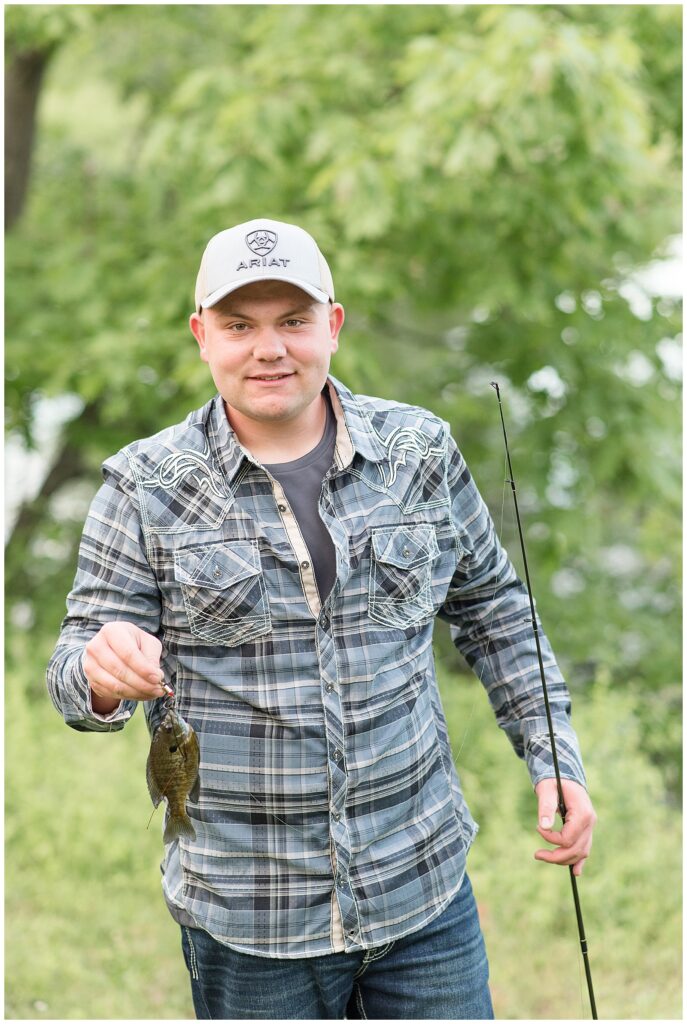 senior guy holding fishing rod in left hand and small fish on hook in right hand at masonic village in lancaster pa