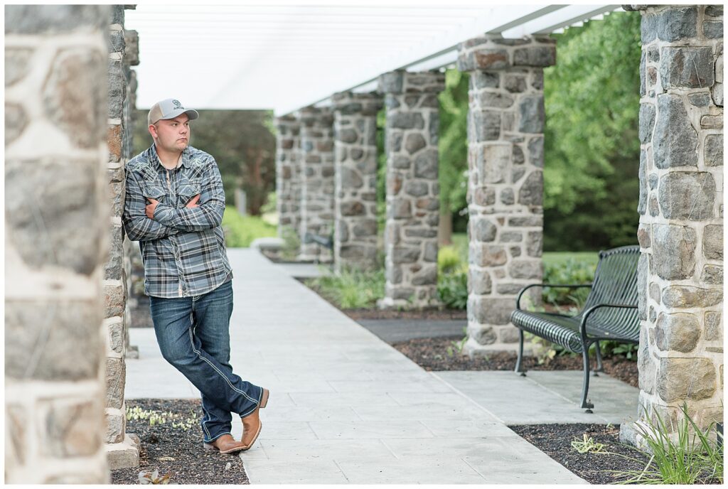 senior guy leaning against stone column and looking left at masonic village in lancaster pennsylvania