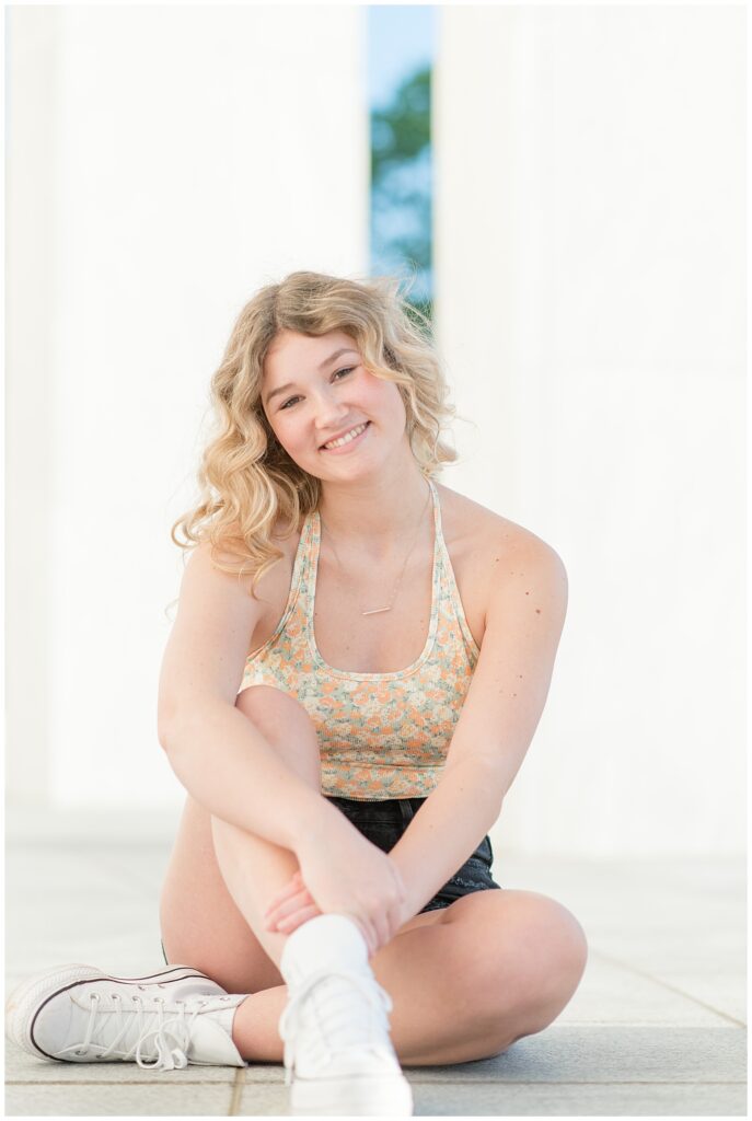 senior girl sitting on the ground as she hugs her bent right leg at founders hall at the milton hershey school