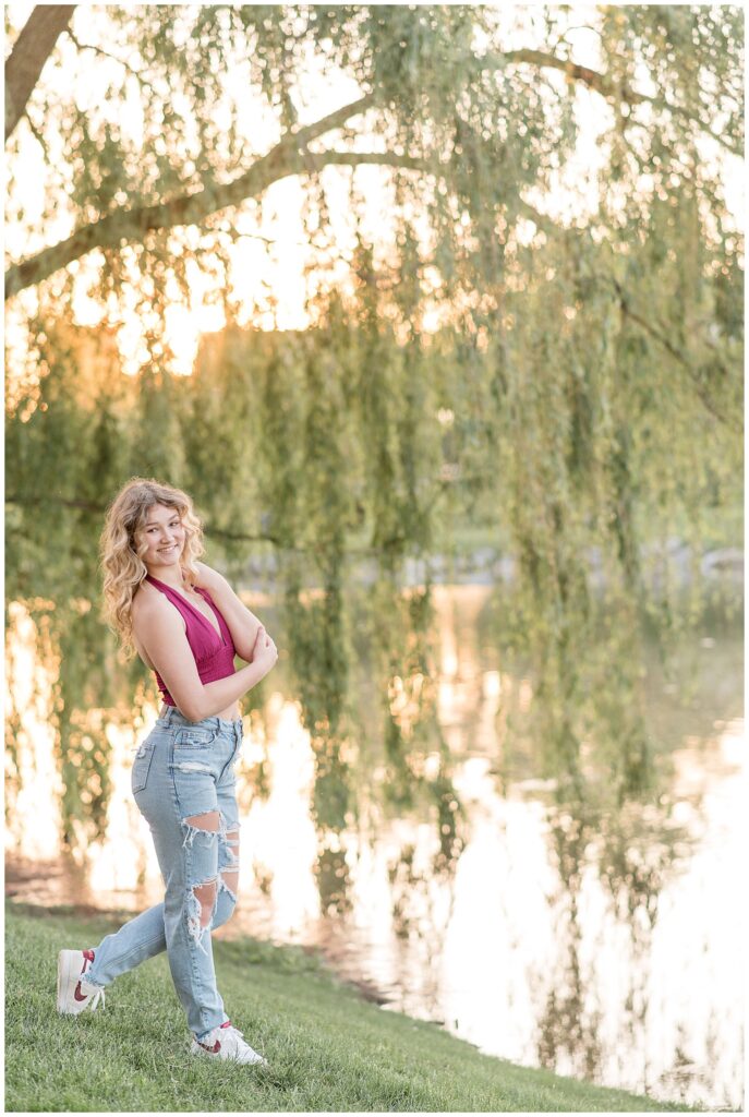 senior girl by willow tree and pond at sunset at milton hershey school in pennsylvania