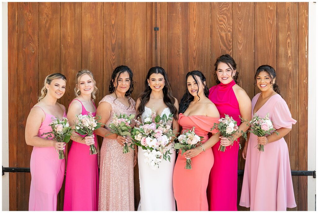 bride and her six bridesmaids in pink dresses holding bouquets at domaine pterion