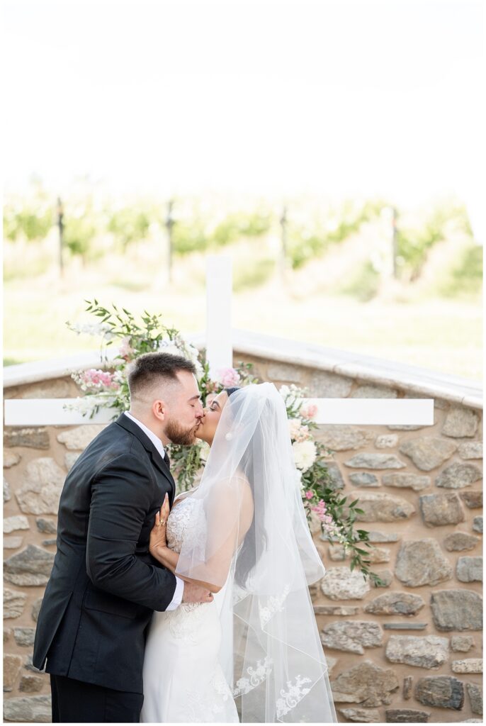 bride and groom sharing their first kiss during outdoor wedding ceremony on sunny spring day in pennsylvania