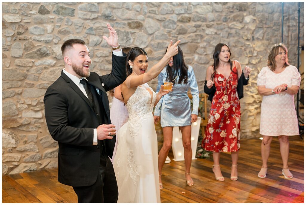 couple cheering during their wedding reception inside stone barn at domain pterion