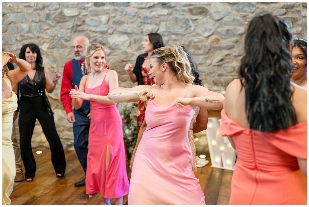 bridesmaids dancing together inside stone barn at reception in lehigh county pennsylvania