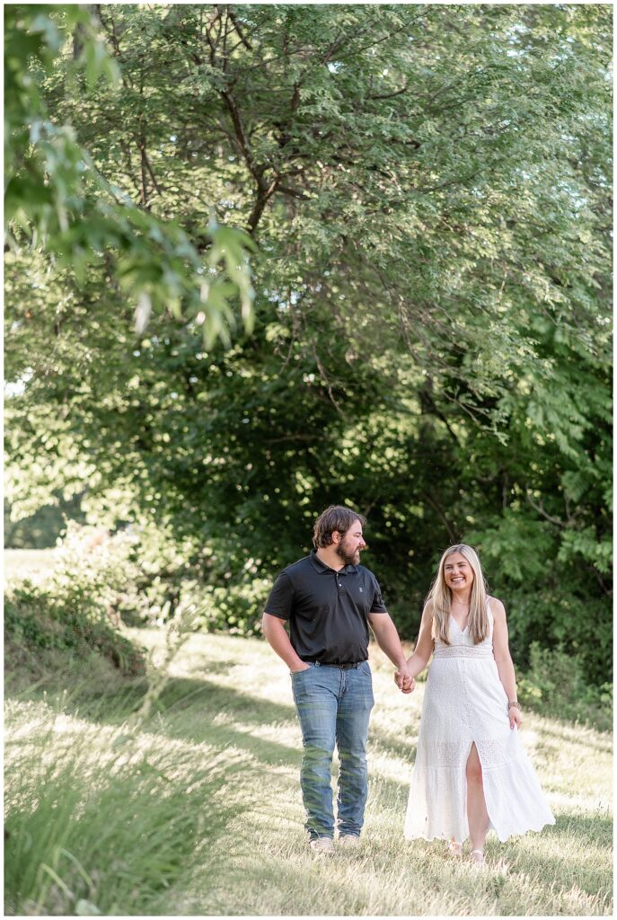 engaged couple holding hands and walking towards camera on sunny evening in wrightsville pennsylvania