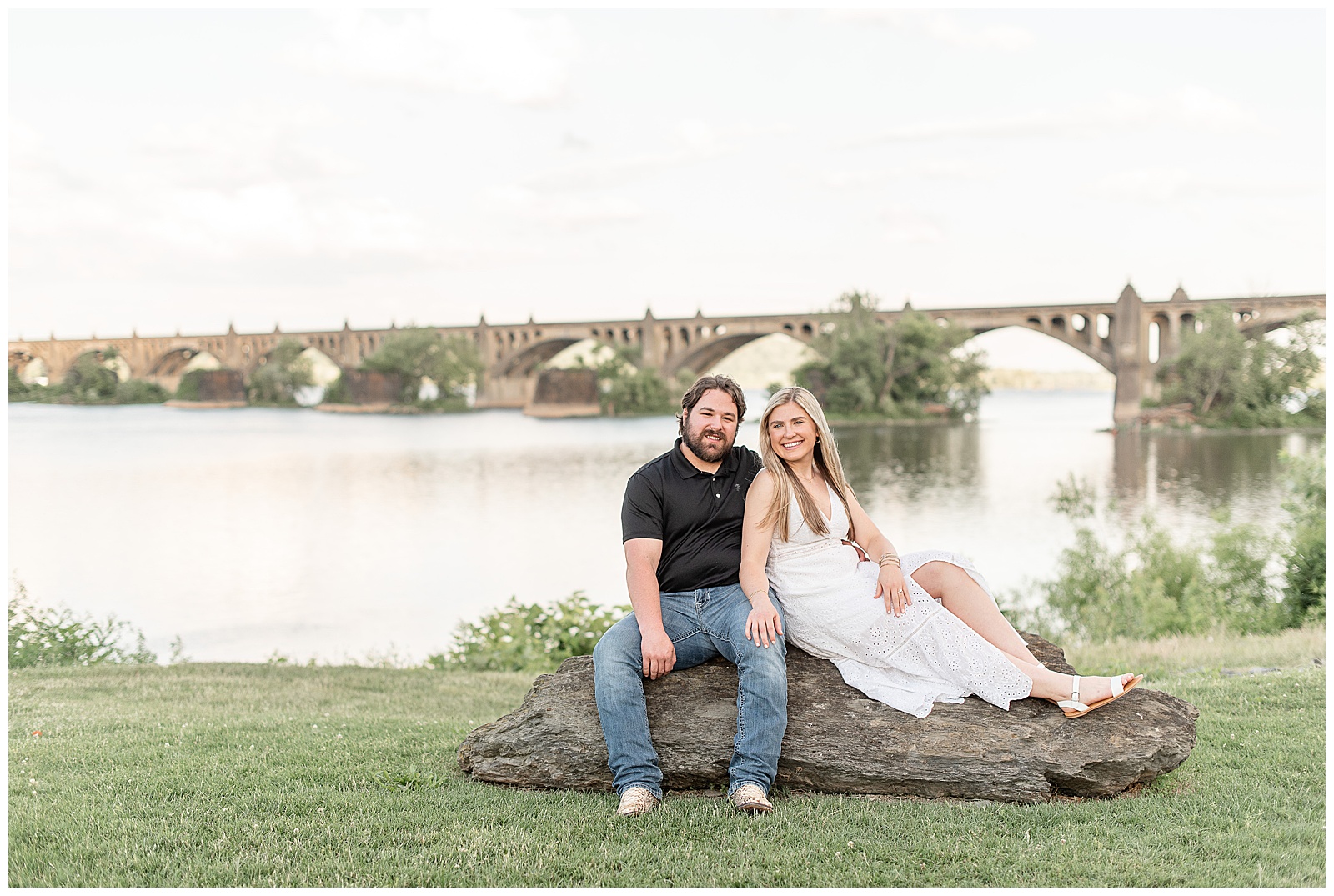 engaged couple sitting on large rock at john wright restaurant by susquehanna river