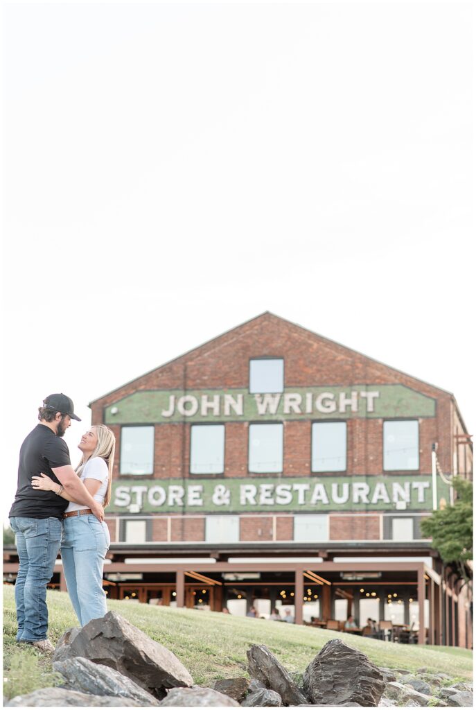 engaged couple hugging in front of historic brick john wright restaurant building in wrightsville pennsylvania