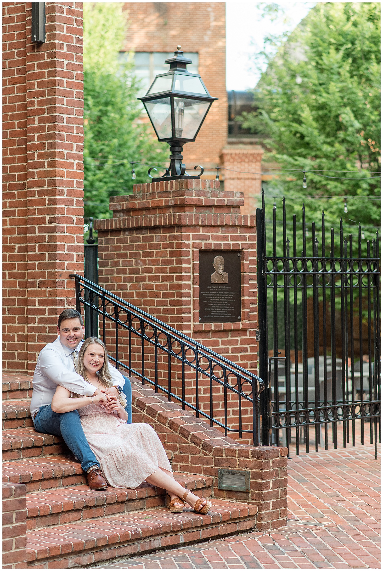 couple sitting on brick steps with woman in front of man as he wraps his arms around her in lancaster pennsylvania