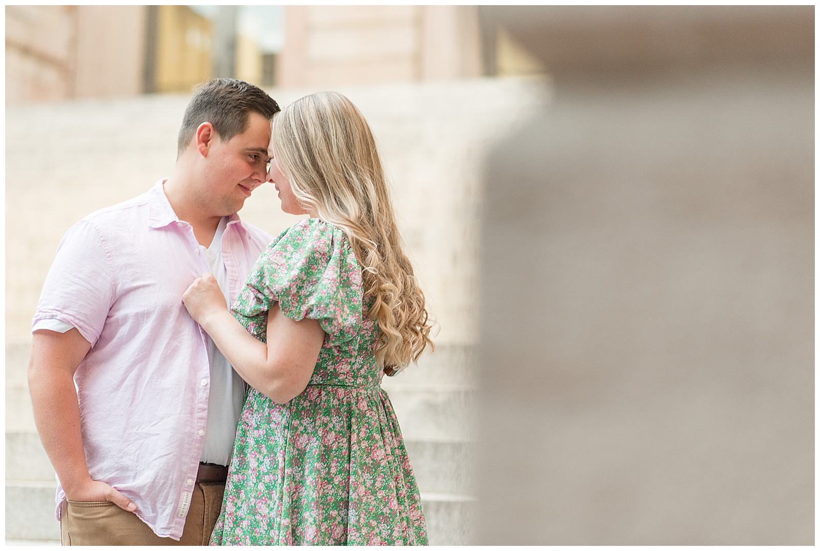 man wearing light pink dress shirt and khaki pants hugging woman in green and pink floral dress in lancaster city