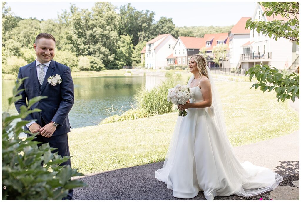 bride approaching her groom from behind before their first look by pond at ironspire complex