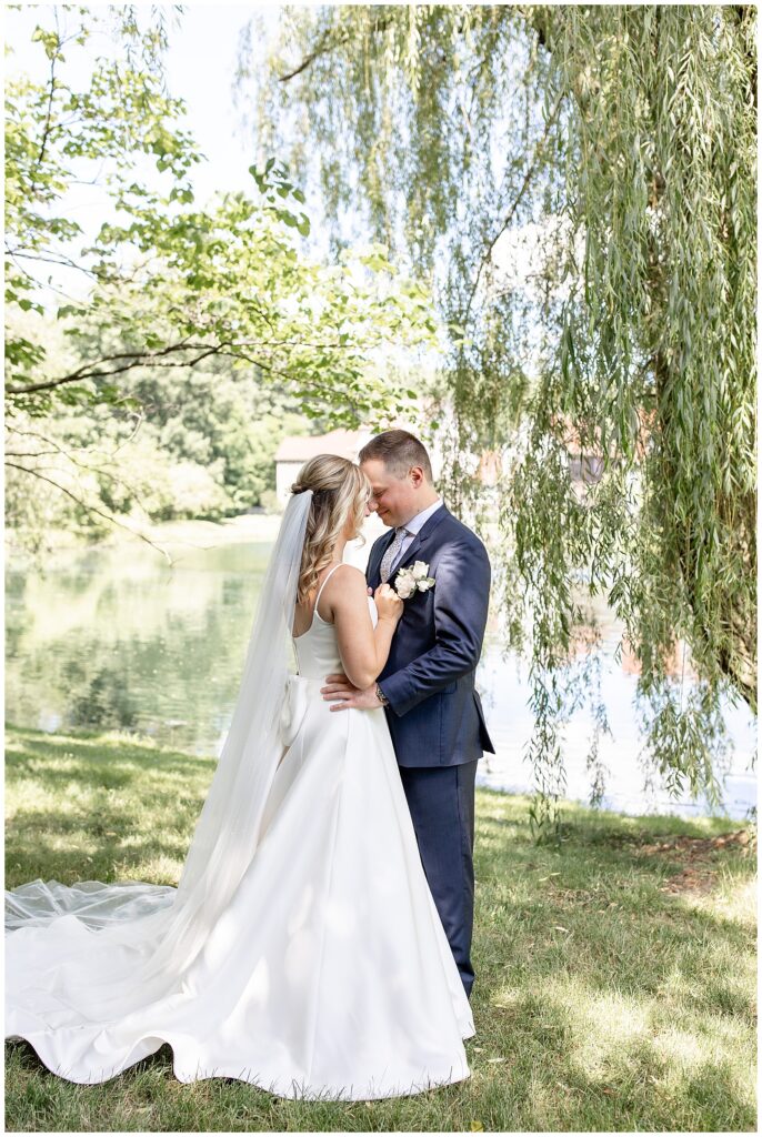 couple hugging with their foreheads touching by willow tree and pond at ironspire complex