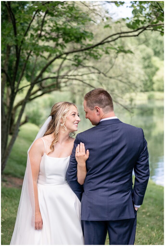 groom's back to camera as bride wraps her left arm through his left arm and they smile at each other in lancaster pennsylvania