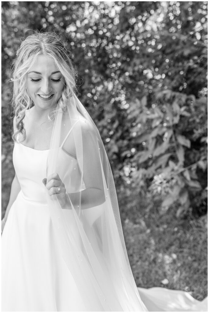 black and white photo of bride holding edge of her long veil at ironspire complex