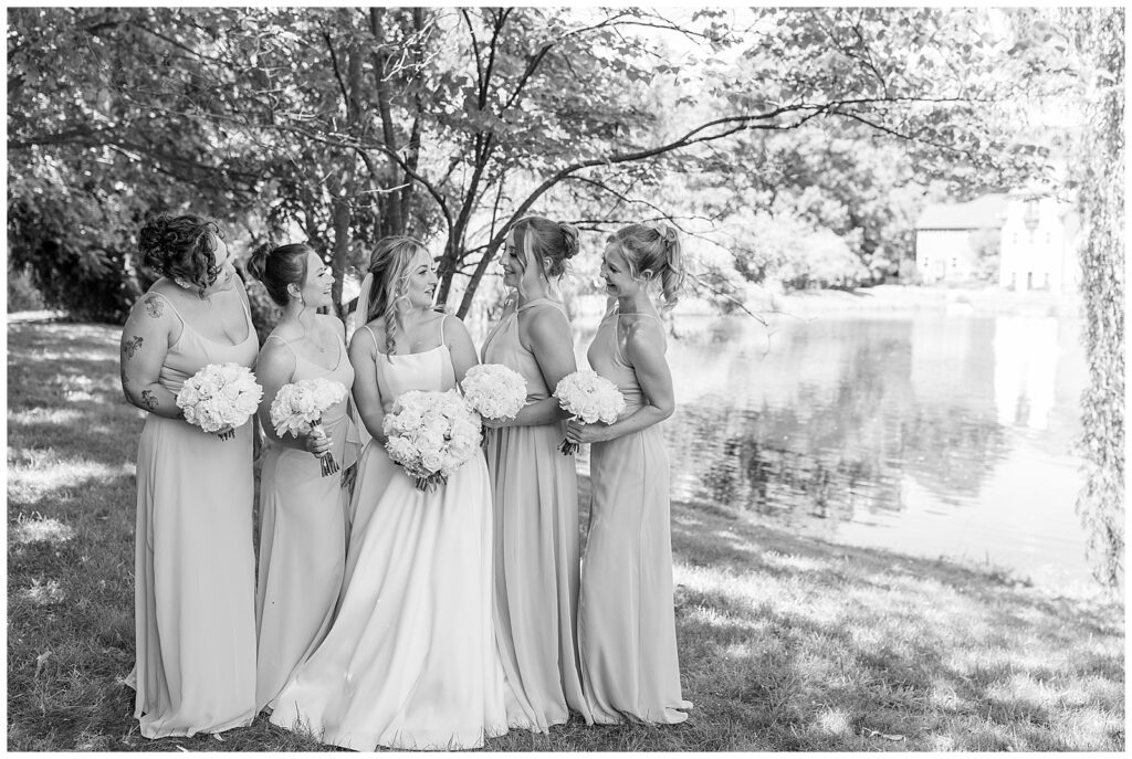 black and white photo of bride with her four bridesmaids as they smile and look at each other at ironspire complex