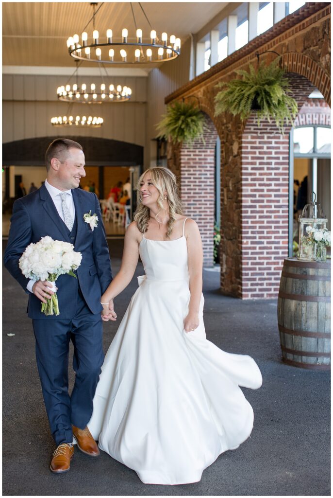 couple walking towards camera holding hands with groom holding bride's bouquet at ironspire complex