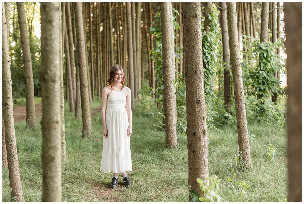 senior girl standing among evergreen trees at overlook park in lancaster pennsylvania